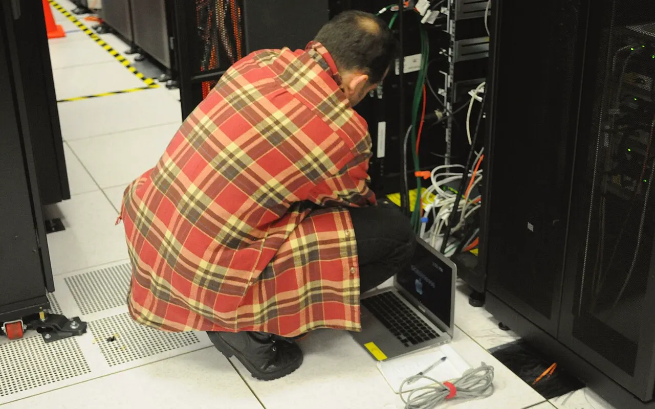 Técnico trabajando con un portátil ante un armario de servidores